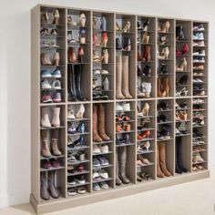 a large closet filled with lots of different types of shoes and boots on shelves next to a white wall