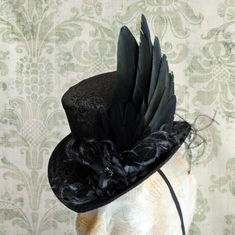 This elegant gothic mini top hat is covered with wonderful black brocade. It is luxuriously decorated with a unique hand-crafted faux raven wing along with curled ostrich spray and black blossoms with crystal details. IMPORTANT NOTE: The fabric seen in the pictures is permanently SOLD OUT! The hat you'll receive will be covered in the brocade seen in the LAST PICTURE. Measurements : height 4 inches( 10 cm ) front to back 9 inches ( 22 cm ) side to side 7.5 inches ( 19 cm ) This mini top hat is f Raven Wings, Steampunk Top Hat, Victorian Hats, Steampunk Hat, Victorian Costume, Mini Top Hat, Elegant Gothic, Mini Top, Diy Hat