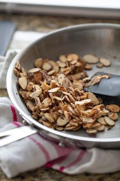 a metal bowl filled with granola on top of a counter next to a spoon