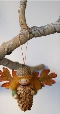 an ornament hanging from a tree branch with leaves and acorns on it