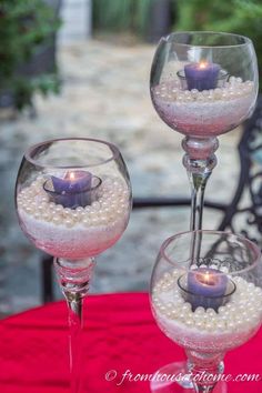 two wine glasses with candles in them on a table