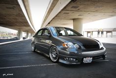 a gray car parked under an overpass in a parking lot