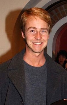 a man with blonde hair smiling at the camera