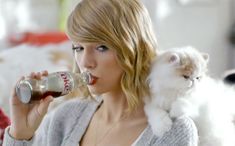 a woman drinking coke with her cat on her shoulder