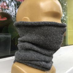 a mannequin head wearing a gray knitted neckwarf on top of a wooden dummy