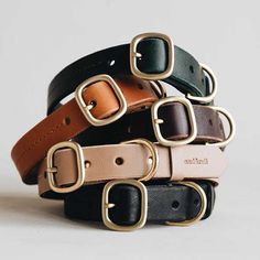 four different colored leather belts stacked on top of each other, with one belt in the middle