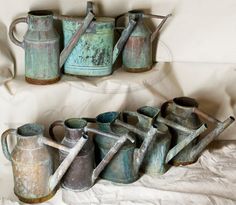 there are many old watering cans and shovels on the bed together, with one leaning up against the wall