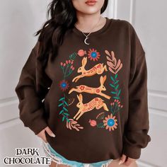 Wrap yourself in cozy magic with this mystical hare sweatshirt, perfect for fans of cottagecore, fairycore, and goblincore aesthetics. Featuring beautifully illustrated hares surrounded by earthy floral patterns, this woodland-inspired design brings a touch of nature's charm to your wardrobe. The relaxed , comfortable fit makes it ideal for layering on chilly days, while the intricate bunny artwork appeals to fans of witchy and mystical fashion. 📝PLEASE CONFIRM📝 Runs true to size. You must siz Bunny Artwork, Animal Sweatshirt, Granola Girl, Cut And Style, Sweat Shirt, Crew Neck Sweatshirt, Comfort Fit, Design Inspiration, Gifts For Her