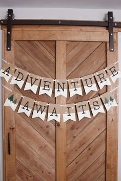 the adventure awaits banner is hung on a wooden door with black and white letters