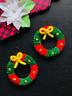 two christmas wreaths made out of yarn on top of a table next to a flower