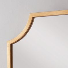 a mirror that is sitting on the wall next to a white wall with a wooden frame