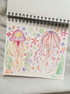 a drawing of jelly fish and starfish on a notepad with colored pencils