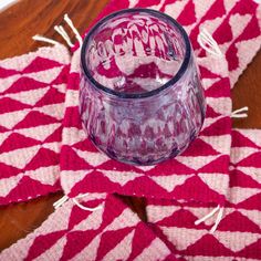 a glass on top of a red and white place mat