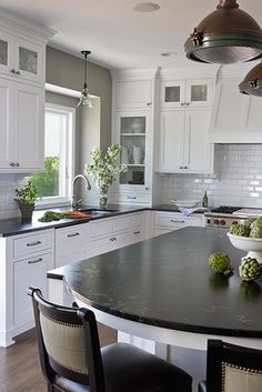 a large kitchen with white cabinets and black counter tops, along with an island in the middle