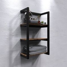 three shelves with towels and plants on them against a white wall in the corner of a room