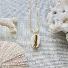 We love this fun and summery, beachy necklace. Answer the siren's song and get one for yourself or someone you love. Would make a great gift for the surfer or beach-lover in your life! A 14k gold electroplated cowrie shell dangles from a lustrous, high quality gold filled snake chain. The perfect summertime accessory! Chain length 16"✦ JEWELRY CARE ✦✧ Warm water and a soft cloth are the best thing you can do to maintain the beauty of your jewelry.✧ Jewelry polishing cloths work great and are non Gold Cowrie Shell As Gift, Gold Cowrie Shell Jewelry For Gift, Handmade Gold Charm Necklace For Vacation, Dainty Strand Jewelry For Beach, Dainty Strand Jewelry For The Beach, Ocean-inspired Gold Charm Necklaces For Summer, Dainty Strand Beach Jewelry, Gold Ocean-inspired Charm Necklaces For Summer, Gold Necklace With Starfish Charm