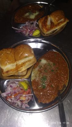 three plates filled with food on top of a metal table next to silver trays