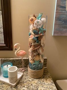 a flamingo is standing next to a vase filled with shells and seashells