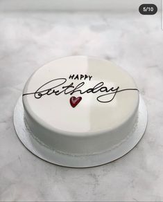 a white cake with writing on it and a red heart in the middle that says happy birthday