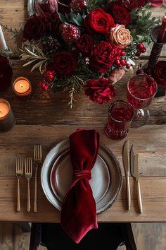 the table is set with red flowers and silverware, candles, and napkins