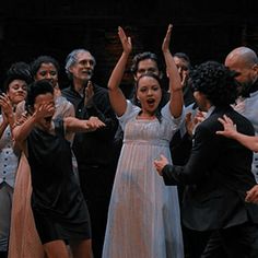 a group of people standing next to each other in front of a crowd with their hands up