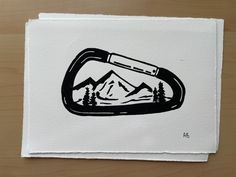 a black and white drawing of a bottle opener on a piece of paper with mountains in the background