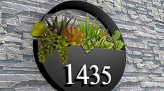 a black circular sign with succulents and the number 1235 on it