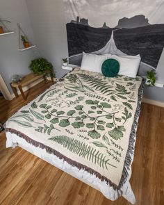 a bed with a green and white blanket on top of it next to a wooden floor