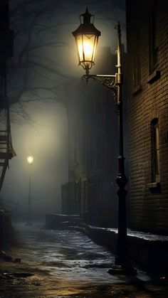 a street light sitting on the side of a road next to a brick building at night