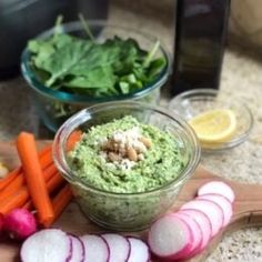 a wooden cutting board topped with carrots and guacamole