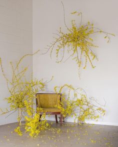 a yellow chair sitting in front of a white wall with lots of yellow flowers on it