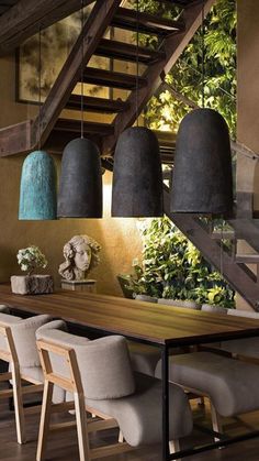 a dining room table with chairs and hanging lights