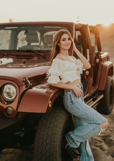 a woman leaning on the hood of a jeep