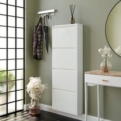 a white cabinet sitting next to a mirror on top of a wall