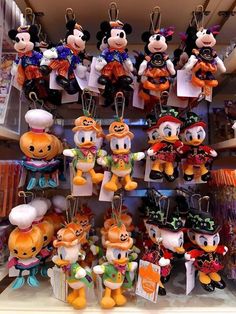 many mickey mouse key chains are on display in a store with pumpkins and other items