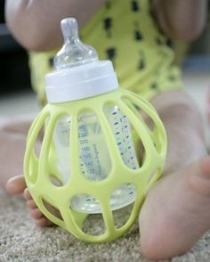 a baby sitting on the ground with a bottle in it's mouth and its feet up