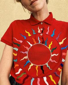 a woman wearing a red shirt with colorful designs on it