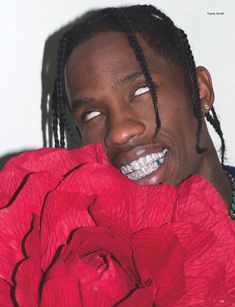 a man with dreadlocks holding a large red flower