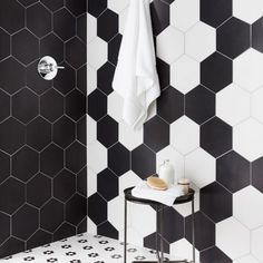 a bathroom with black and white tiles on the walls, flooring and shower head