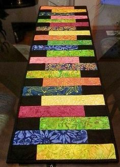 a long table with many different colored strips on it and a vase in the background