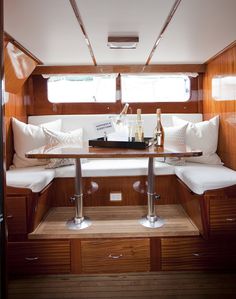 the interior of a sailboat with wooden paneling and white cushions on the bench