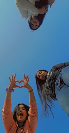 three women standing in the air making a heart shape with their hands