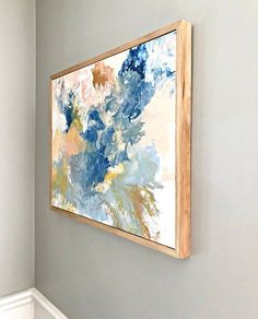 a painting hanging on the wall above a toilet in a room with white walls and wood trim