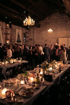 a group of people standing around tables with candles on them