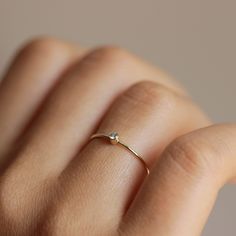 a woman's hand with a gold ring on top of her finger and a diamond in the middle