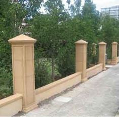 a row of stone pillars on the side of a road with trees in the background