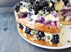 a cake with blueberries and blackberries on it is cut in half to show the layers