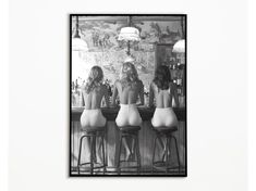 three women sitting at a bar with their backs turned to the camera, in front of a mirror