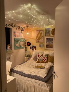 a bed room with a neatly made bed and lots of pictures on the wall above it