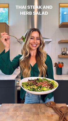 a woman holding a plate of food with the words thai steak and herb salad on it